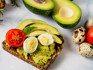 Vegan sandwich with avocado and vegetables on a light background.