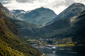 Trip to Norway. Panoramic view of Geiranger town and mountain Dalsnibba with big ferry on fjord from the Eagle's road in the cloudy summer day