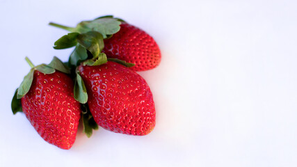 three large ripe fresh strawberries lie on a white background
