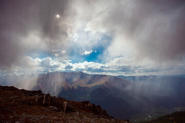 rain in the mountains with breaking rays of the sun from the clouds