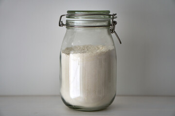  Glass jars with a lid for food on a white shelf. Storage in the kitchen. Containers with bulk products. Transparent container.