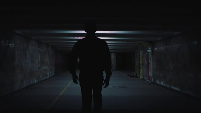 a man walks in the evening lighted underpass