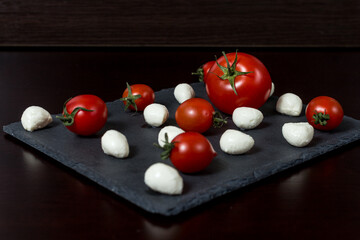 tasting cheese. mozzarella cheese balls and cherry tomatoes on a cheese platter.