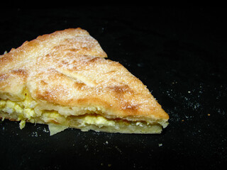 a slice of lemon pie on a dark background.