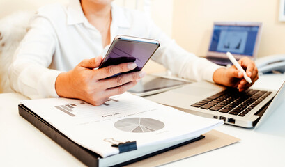 Businesswoman hands working with finances about cost and calculator and laptop with tablet, smartphone at office in morning light