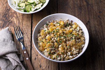Traditional Middle Eastern dish, Mujadara of lentils, rice and fried onions with a salad of cabbage and cucumbers on wooden table, top view, selective focus