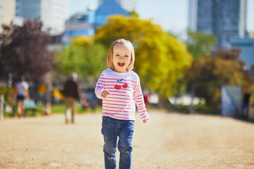 Cheerful toddler girl running on a street of Paris, France
