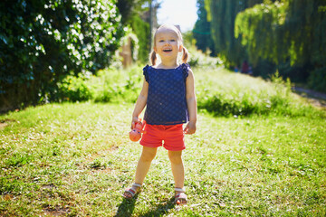 Adorable toddler girl walking in park or forest