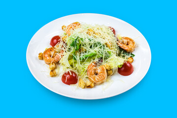 Caesar salad with royal prawns isolated on blue background