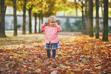 Adorable cheerful toddler girl running in Tuileries garden in Paris