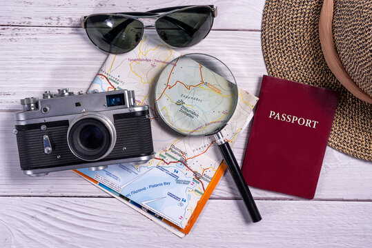Top view traveler accessories on wooden background. Flat lay vintage camera, sunglasses, map, magnifying glass, straw hat and passport document. Travel planning concept