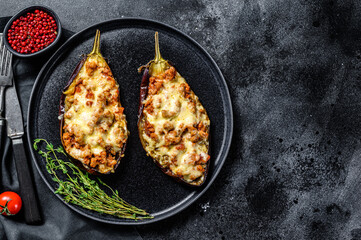 Baked eggplant with tomatoes and cheese. Black background. Top view. Copy space