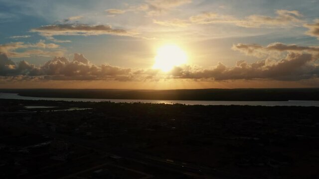 Beautiful aerial drone right trucking shot of a gorgeous golden sunset with a large amazonian river below in Joao Pessoa, Brazil.