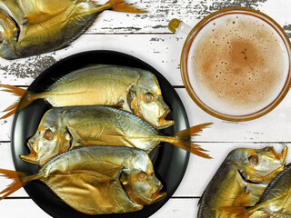 Cold smoked moonfish (vomer or lookdown fish) with glass of frothy beer on white wooden table top...