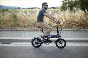 Caucasian attractive man rides his e - bike on the street to go to work and in his leisure. Electric bibycle concept. Ecologic mobility concept. Modern transportation. Electric biking . Cycling man 