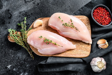 Fototapeta Raw chicken breast fillet on a chopping Board with herbs and spices. Black background. Top view obraz