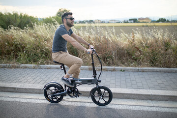 Caucasian attractive man rides his e - bike on the street to go to work and in his leisure. Electric bibycle concept. Ecologic mobility concept. Modern transportation. Electric biking . Cycling man 