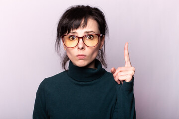 girl in a green turtleneck, glasses, portrait on a gray background