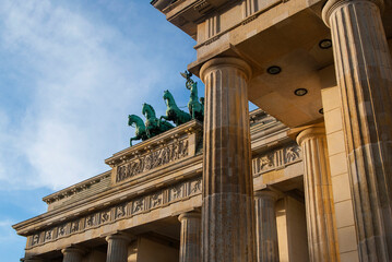 Brandenburg Gate in Berlin, Germany on a sunny day against a blue sky. A statue of chariots with horses nearby. © Hanna