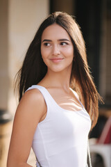 Fototapeta premium Portrait of young woman standing by the cafe. Woman wait for shop coffee. Happy smiled woman after quarantine
