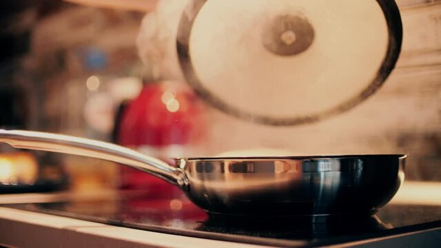 Opening hot sizzling steel fry pan on stove top. Cooking at home