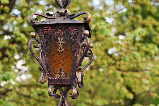 Forged metal street lantern in the park with blurred background