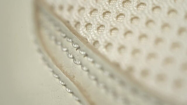Extreme close up stitching on sneakers leather beige. Dolly out footage.
