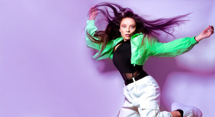 Girl brunette with long hair on a purple background jumps, flies. Dancing, hip hop.
