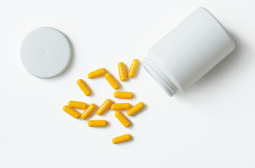 An open bottle with yellow tablets on a white background. The view from the top.