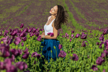 Obraz na płótnie Canvas happy beautiful woman in the sunny summer field of purple poppy flower 