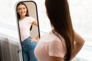 Happy Skinny Girl Looking At Reflection In Mirror At Home