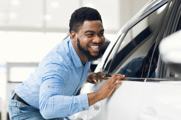 African Guy Touching His New Vehicle In Dealership Showroom