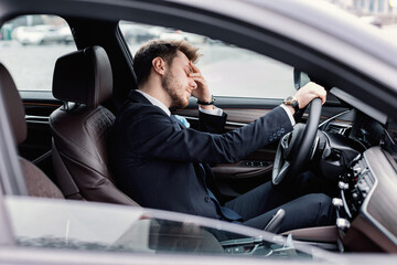 Sad businessman driving alone in his new car