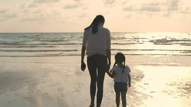 Family concept. Mother holding her daughter to walk by the sea. 4k Resolution.