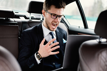 Young businessman using laptop sitting in car