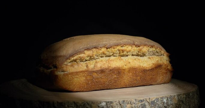 sourdough bread, Dynamic closeup of real bread baked according to old local prescriptions on a wooden board in warm colors on a black background