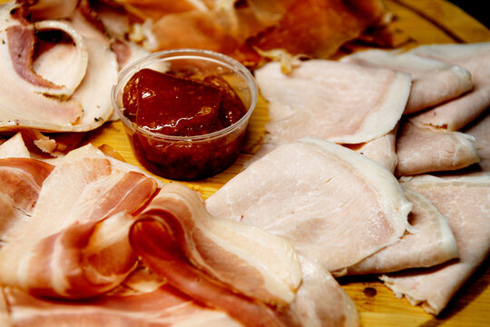 Assorted meat, thin sliced meat. Products lie on a round wooden board.