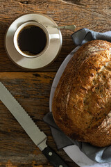 Artisan bread with cutting knife and coffee on aged wooden background. Top view