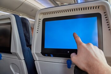 Using the seatback screen on a plane trip, watching movies, displaying flight data. Finger on blank...