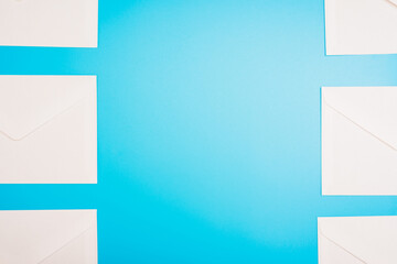 Blue background with white paper envelopes with empty space in the center.