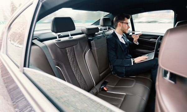 Young businessman talking on phone in luxury car