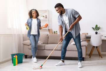 Household Concept. Happy Black Couple Enjoying Cleaning House Together