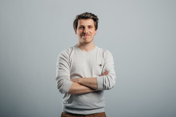 Medium shot portrait of smiling young man in white shirt on grey background