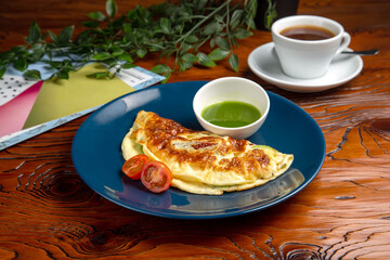 Egg omelet, pesto sauce, black coffee. Breakfast is on the table.
