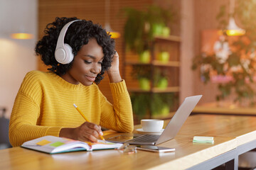 Smiling black girl with headset studying online, using laptop - obrazy, fototapety, plakaty
