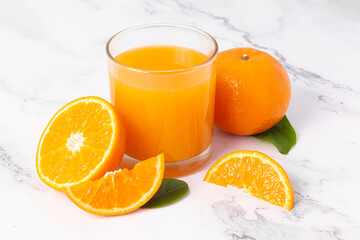 Fresh orange juice in glass and oranges fruit on white marble table background.