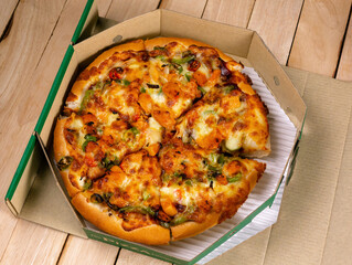 Pizza in a cardboard box against on wooden table background Ready to Eat