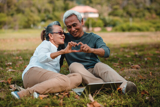 Romantic senior couple. sitting resting and grandparents make symbol of love by using hands. Love is everything, background and image not focus..Retirement age concept and love, copy space for text