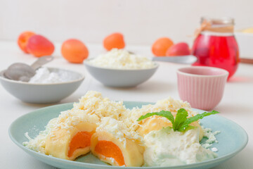 Fruit dumplings stuffed with apricots, sprinkled with cottage cheese and sugar, topped with melted butter, with creme fraiche with grated lime zest and embellished with mint. Hibiscus tea in glass.