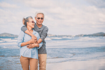 Romantic of senior couple smile and hugging each other while standing together at daytime on beach near sea..Retirement age concept and love, copy space for text